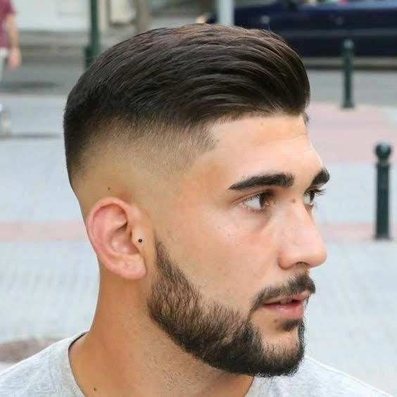 Corte de pelo alto degradado con un partido duro, creando un estilo limpio y estructurado que resalta los rasgos faciales.