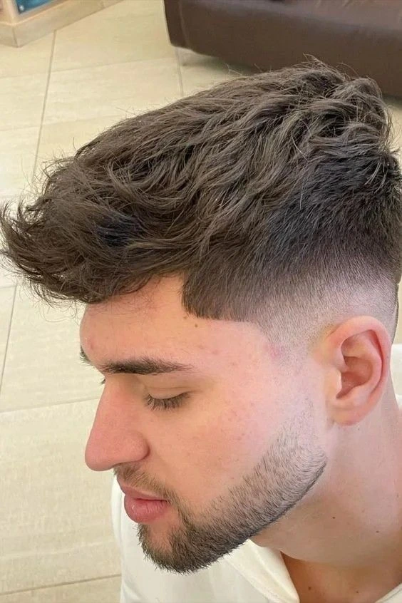 Corte de pelo alto degradado con textura en la parte superior, dando volumen y estilo moderno a la parte superior del cabello.