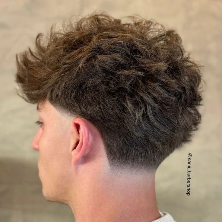 Corte de pelo low fade con mechas destacadas, combinando un degradado suave con luces brillantes para un estilo llamativo y elegante.