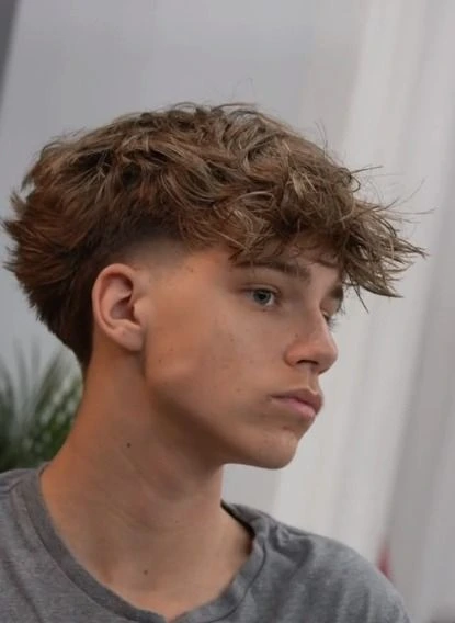 Corte de pelo low fade desordenado, con un estilo relajado y moderno que combina el corte limpio con un toque de informalidad.